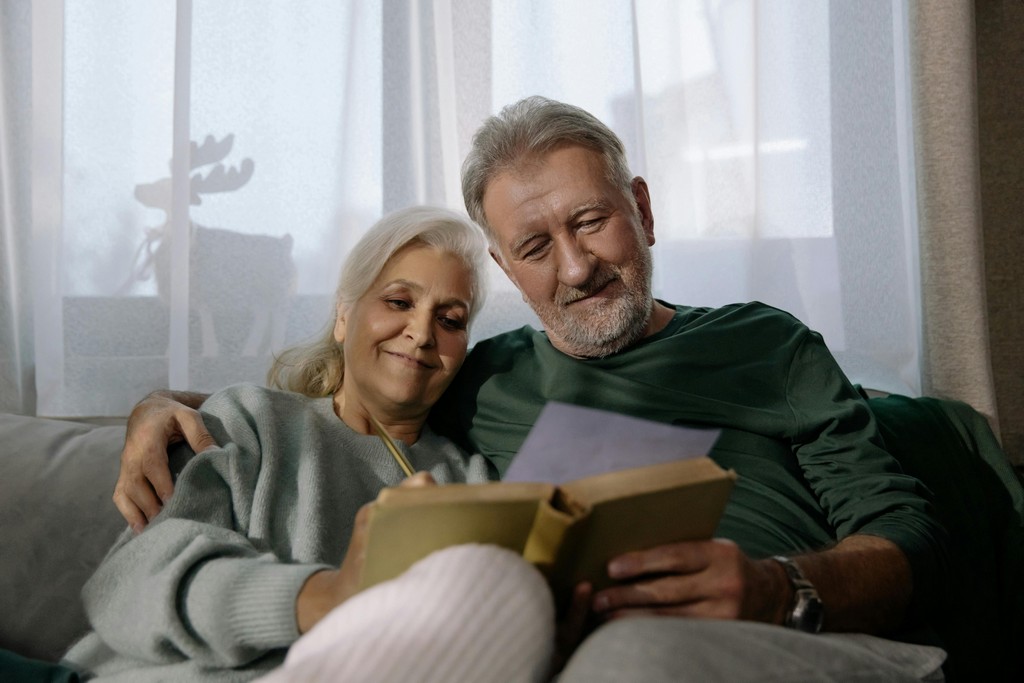 A couple smile and embrace as they look at a notebook.