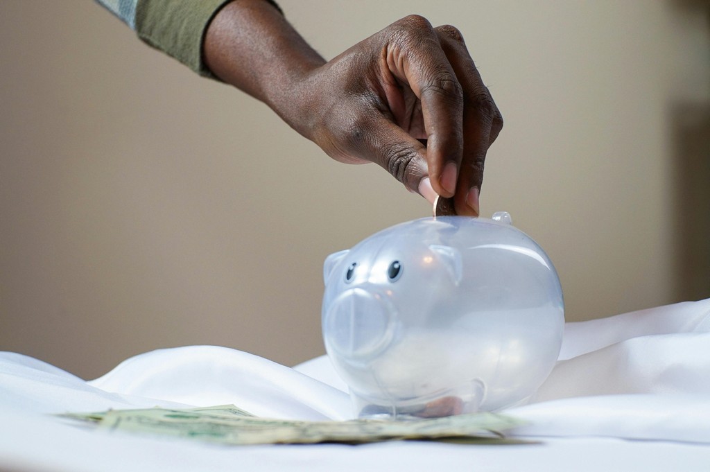 A person puts a coin into a piggy bank.