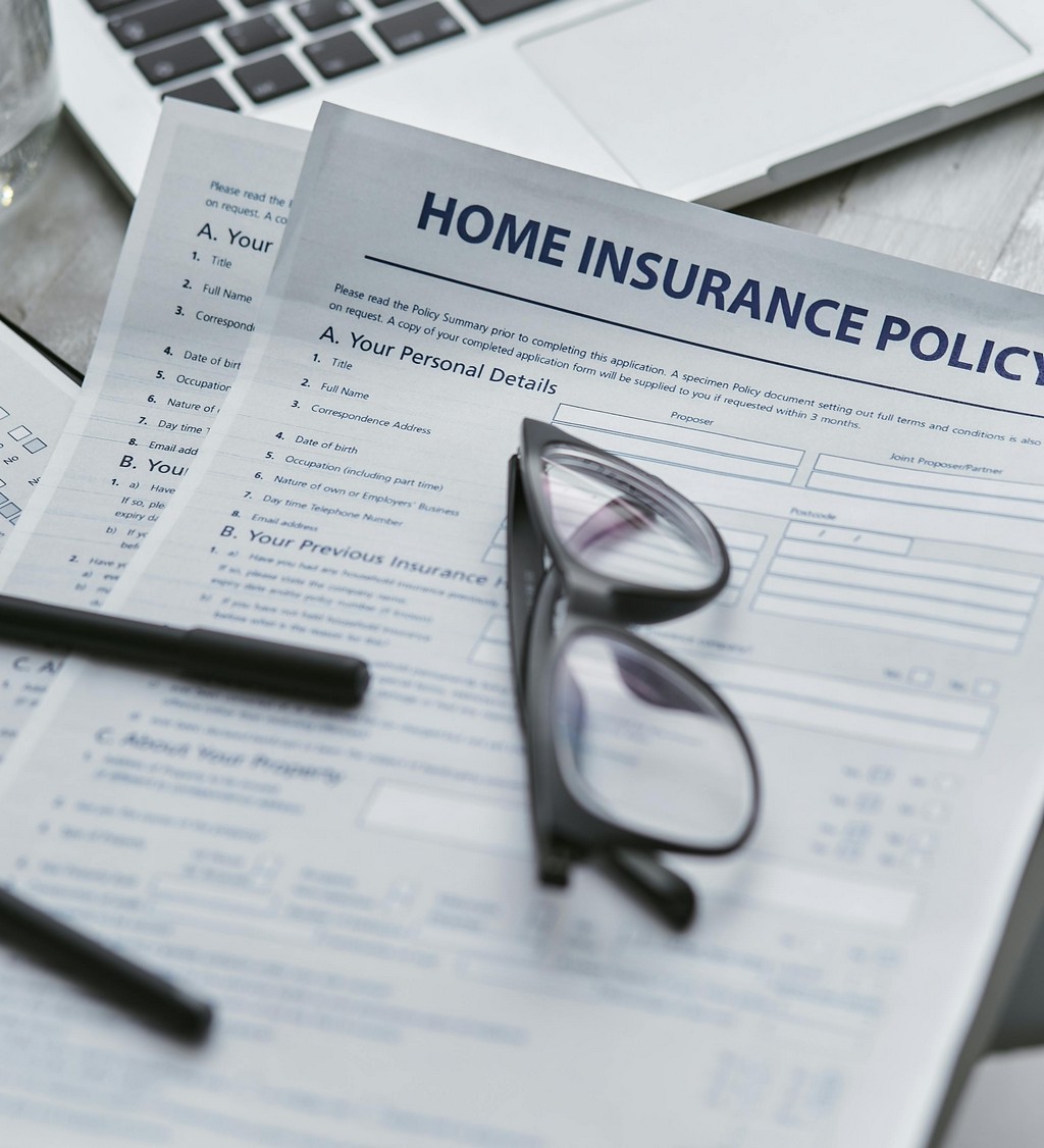 An insurance contract lays on the table, with a pen and pair of glasses.