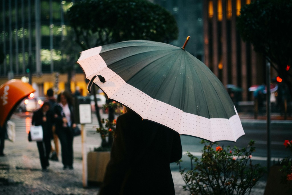 A person is walking in the rain, but their umbrella keeps them dry.