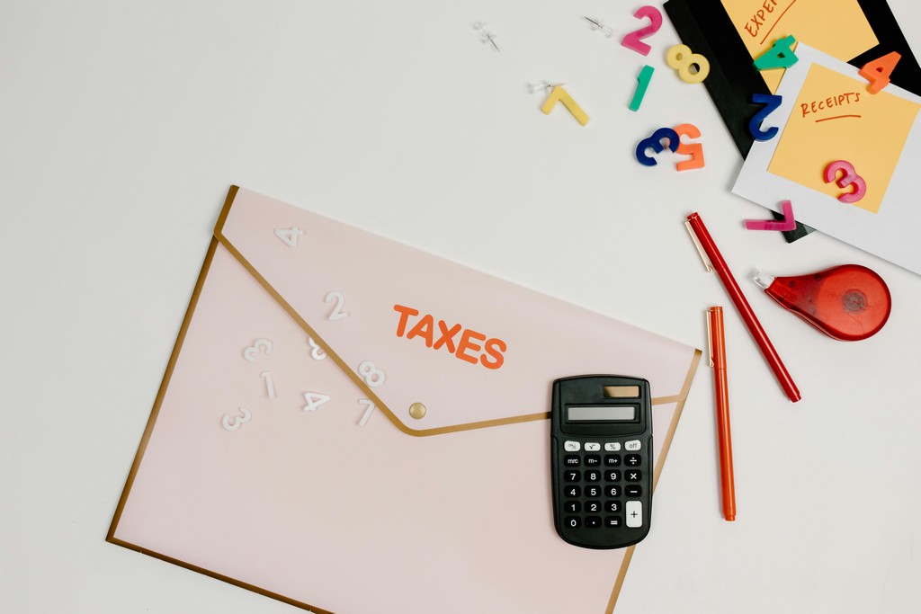 A desk full of stationery shows a folder labeled Taxes.