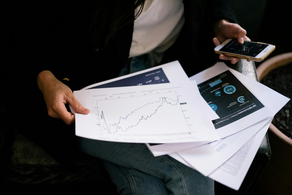 A person looks at a pile of financial reports.